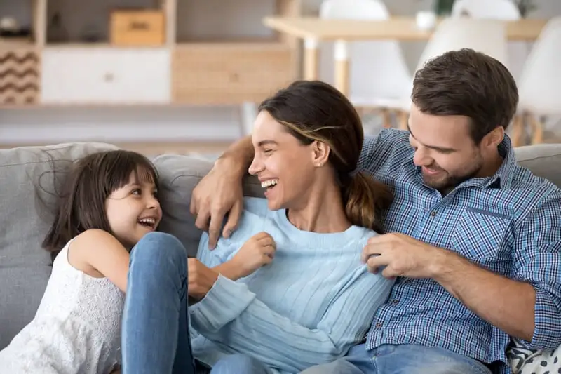 Happy family sitting on a couch, representing the support offered by Dilworth Center's addiction recovery programs in Charlotte, NC.