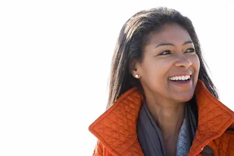 Smiling woman in an orange coat, representing positive outcomes from addiction treatment in Charlotte.