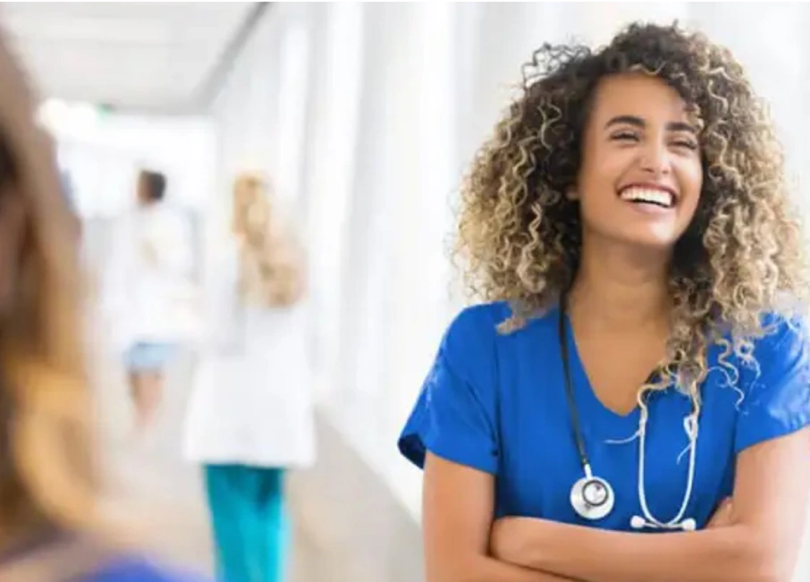 Adult Nurse leaning against a window and laughing at work