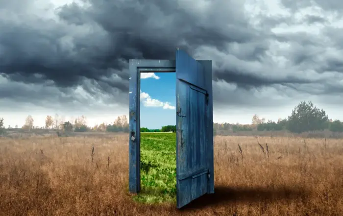 A symbolic doorway in a stormy field opening to a vibrant landscape, illustrating the journey from addiction to sobriety through outpatient alcohol rehab and the benefits of stopping drinking.