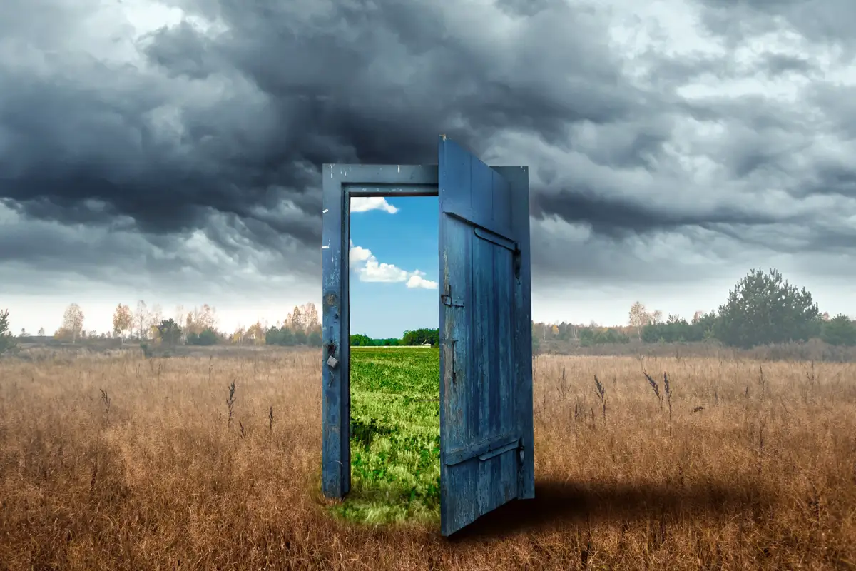 A symbolic doorway in a stormy field opening to a vibrant landscape, illustrating the journey from addiction to sobriety through outpatient alcohol rehab and the benefits of stopping drinking.