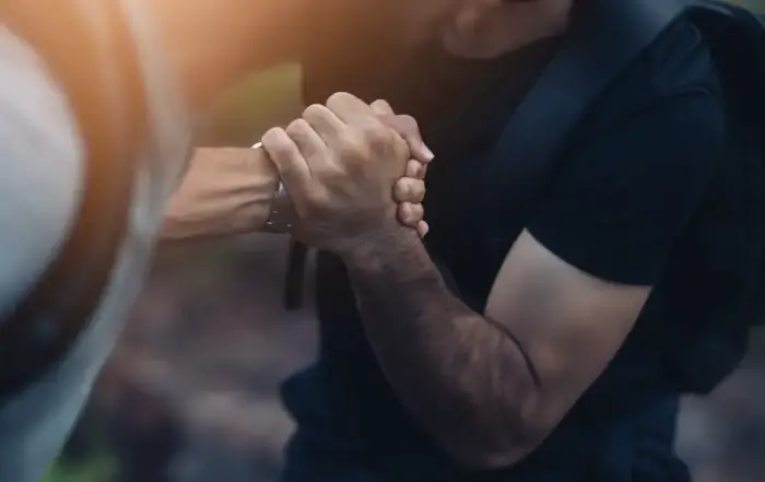 A close-up of two hands clasped together in support, representing assistance during the difficult journey of opiate withdrawal and recovery from painkiller addiction.