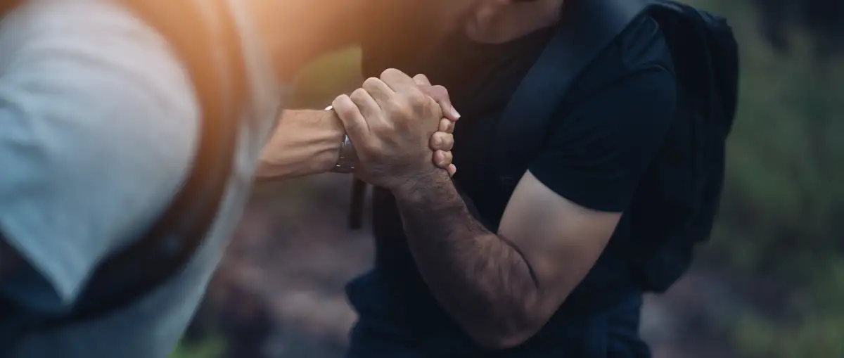 A close-up of two hands clasped together in support, representing assistance during the difficult journey of opiate withdrawal and recovery from painkiller addiction.