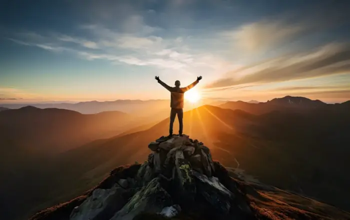 Person with arms raised on a mountain summit at sunrise, symbolizing emotional stability and mental clarity achieved from quitting weed.