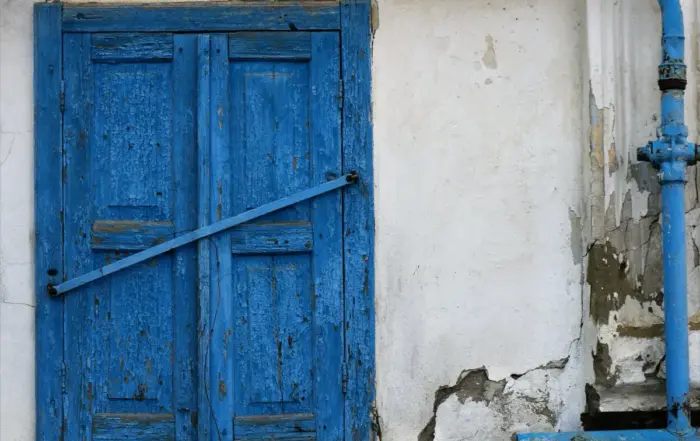 An old blue shuttered window on a weathered wall, illustrating methamphetamine withdrawal symptoms.