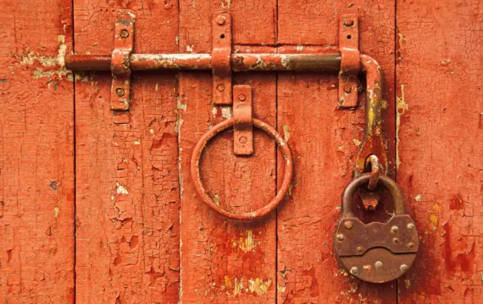 Rusty lock on a red wooden door, symbolizing kratom addiction and the struggle to quit.